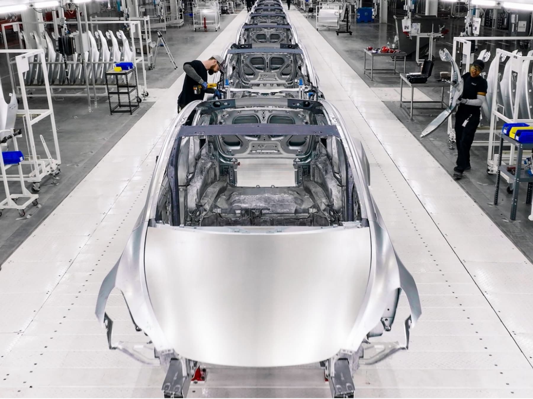 De productie van auto's in een Tesla-fabriek. Hoe kan het dat de fabrikant keer op keer zijn prijzen verlaagt?