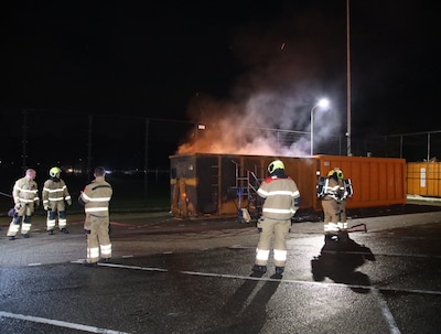 Jongens gooien vuurwerk in container, vlammen slaan hoog uit