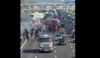 Gemaskerde hooligans lopen met rode fakkels over A4 en houden spelersbus Ajax tegen