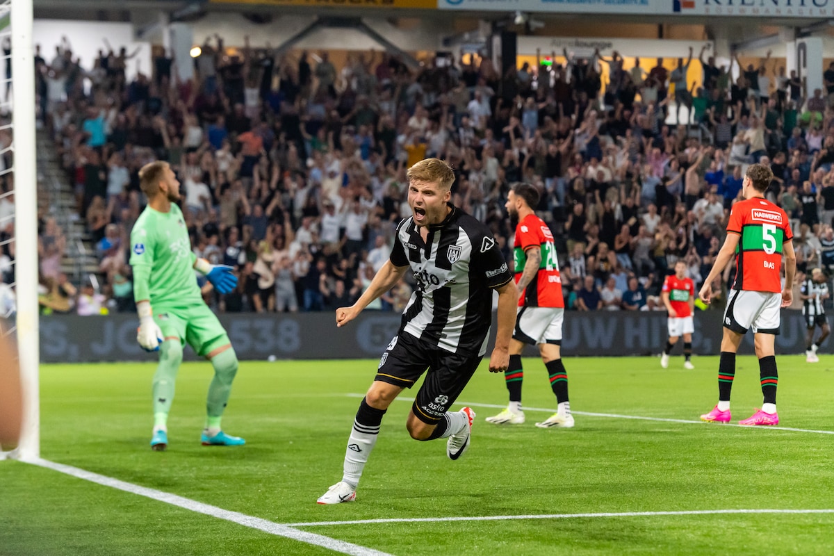 Heracles Almelo-aanvaller Emil Hansson juicht na zijn gelijkmaker, terwijl de spelers van NEC op de achtergrond treuren.