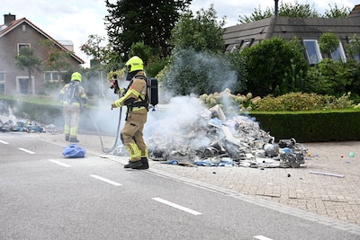 Vuilniswagen dumpt brandende lading afval op straat in Herwen, weg dicht