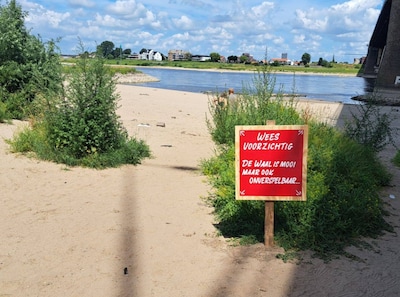 Met dit opvallende bord wil De Kaaij zwemmers waarschuwen voor de gevaren van de Waal