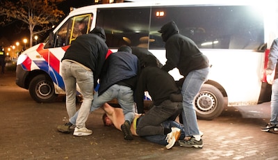 Wie zijn toch die mannen met capuchontruien die in een flits de ergste relschoppers een busje intrekken?