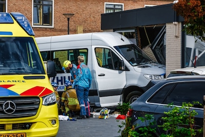 Taxibus rijdt gebouw binnen, persoon komt onder voertuig terecht