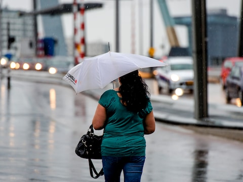 Een voetganger op de Erasmusbrug trotseert de regen.