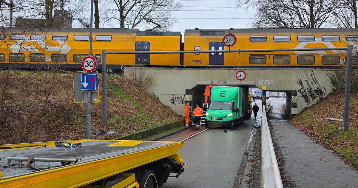Kleine vrachtwagen zit klem onder viaduct