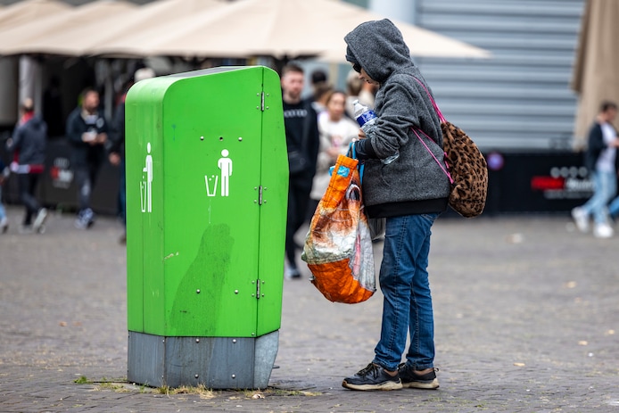 een-man-haalt-blikjes-en-plastic-flesjes-uit-een-afvalbak-beeld-ter-illustratie