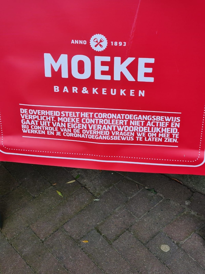 De borden voor de ingang van Moeke, waar de gemeente Nijmegen naar verwijst. Hierop maakt het restaurant duidelijk de coronatoegangscheck niet al te streng te hanteren.